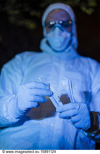Arzt  der Schutzkleidung trägt  hält Virusabstrich-Test