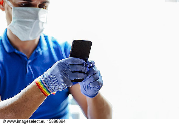 Arzt mit Gesichtsmaske  mit Smartphone