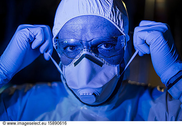 Arzt trägt Schutzkleidung  legt Gesichtsmaske an