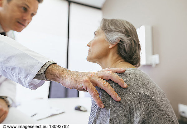 Arzt tröstet ältere Frau in medizinischer Klinik