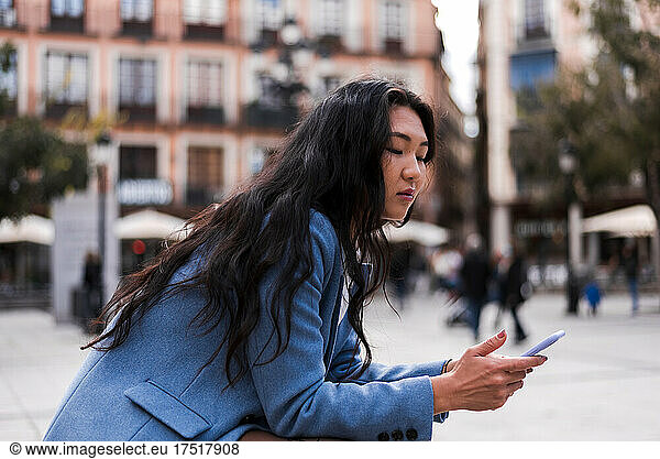 Asian businesswoman sitting in a square with her mobile phone