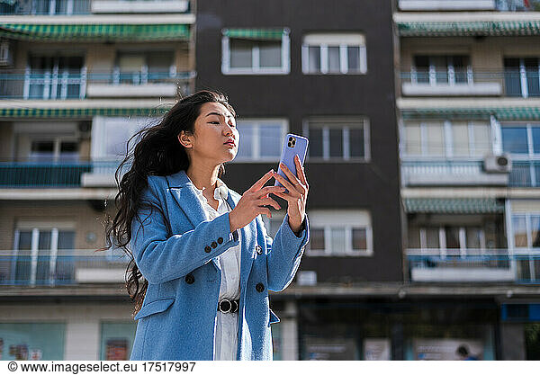 Asian businesswoman with her mobile phone in a residential area.