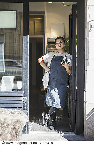 Asian female employee standing at doorway in store