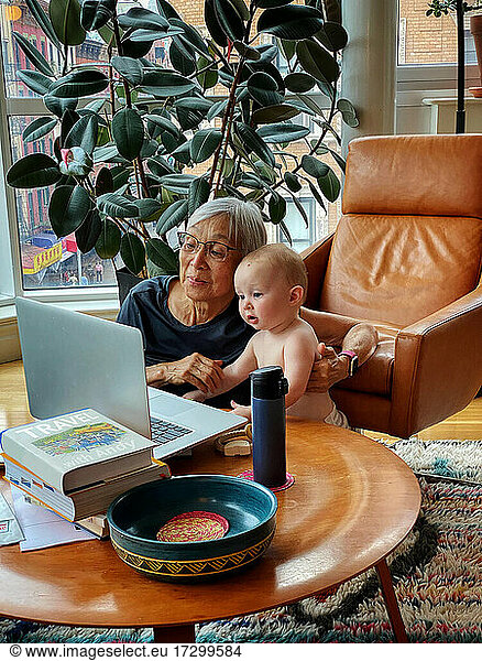 Asian Grandmother and Granddaughter using laptop together at home