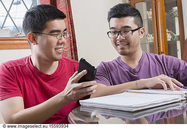 Asian man with Autism showing phone to his brother