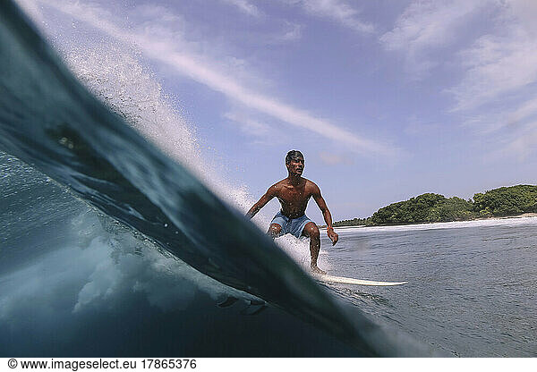 Asian surfer on a wave at sunny day