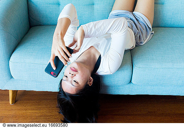 Asian teenage girl lay down using mobile phone