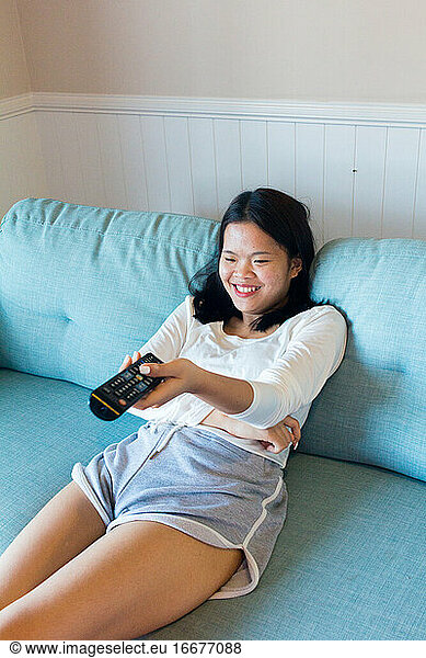 Asian teenage girl sitting laugh watch television