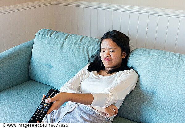Asian teenage girl sitting on sofa watch television