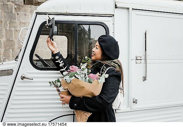 Asian woman checking her appearance in a mirror of a van