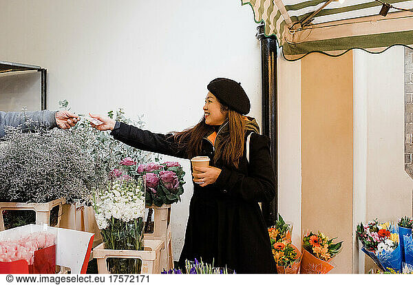 Asian woman paying for flowers at a street market