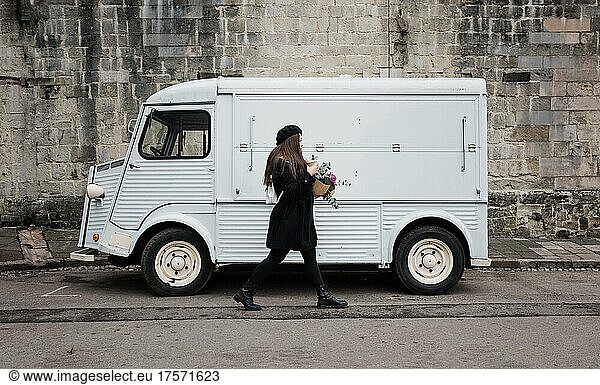 Asian woman walking past a vintage van with flowers and coffee