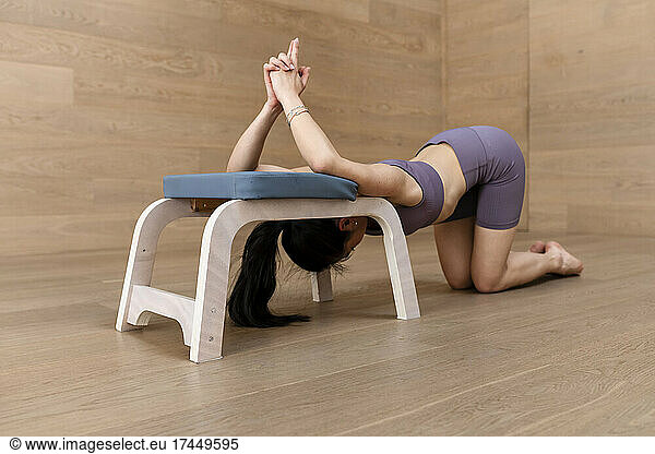 Asian yogi woman is practicing yoga on a feet up stool