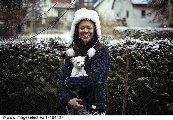 Asiatische Frau lächelt in die Kamera weißen weißen flauschigen Hut und weißen Hund Hund