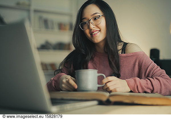 asiatische Frau lächelt mit einem Laptop