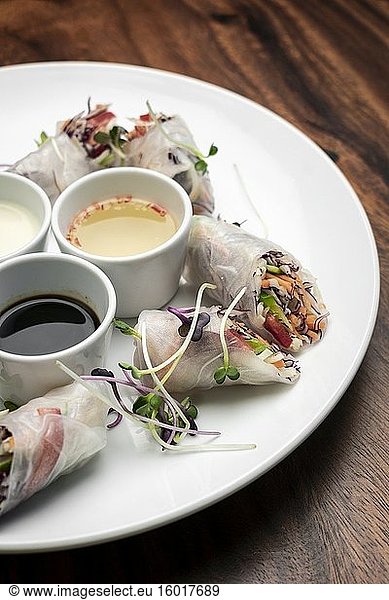 Asiatische frisches Gemüse vegane Frühlingsrollen mit Saucen auf Holz Restaurant Tisch Hintergrund in vietnam.