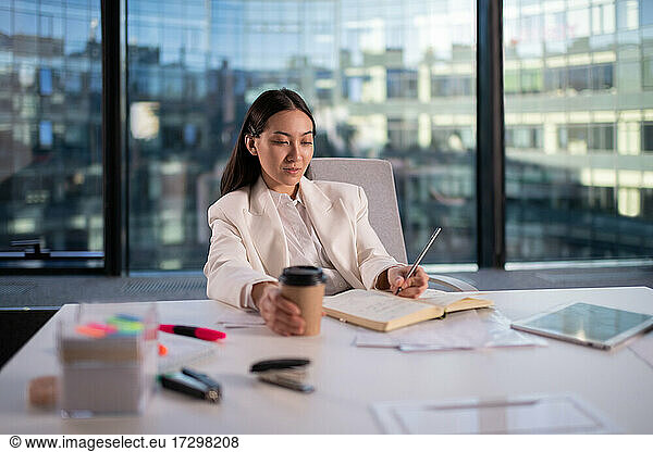 Asiatische Geschäftsfrau macht Notizen im Büro