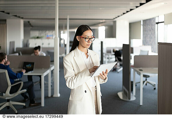 Asiatische Geschäftsfrau mit Tablet am Arbeitsplatz
