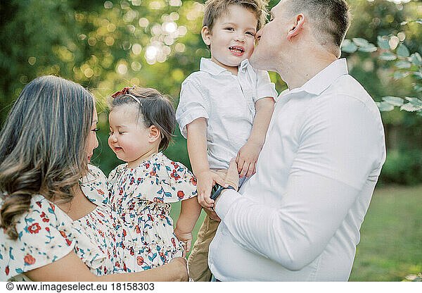 Asiatische Mutter hält Tochter  weißer Vater hält Sohn.