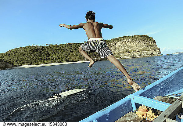 Asiatischer Surfer springt ins Meer