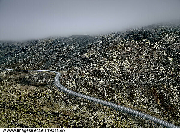 Asphalt road in mountainous terrain in fog