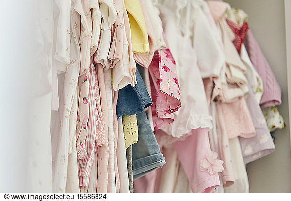 Assortment of baby clothing hung inside cupboard