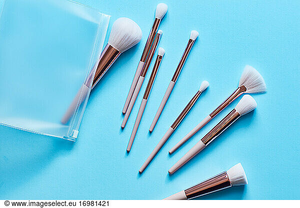 Assortment of Makeup brushes on turquoise surface