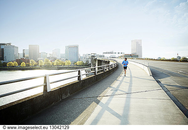 Athlet schaut weg  während er in der Stadt auf einer Brücke läuft