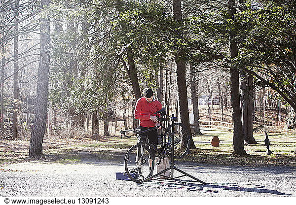 Athlete adjusting bicycle on road during sunny day