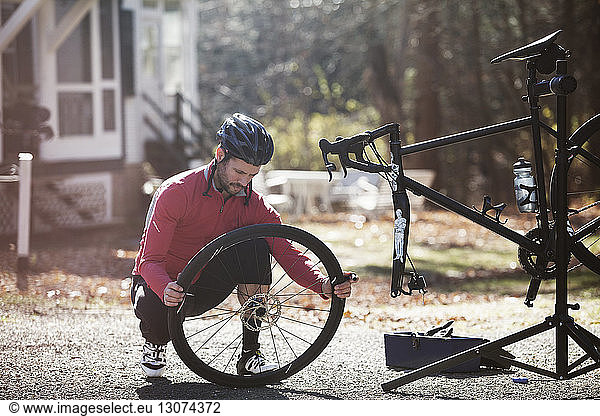 Athlete adjusting bicycle tire on road during sunny day