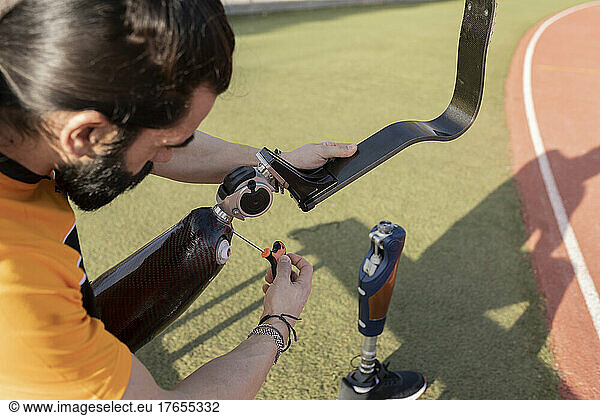 Athlete adjusting prosthetic leg with screwdriver