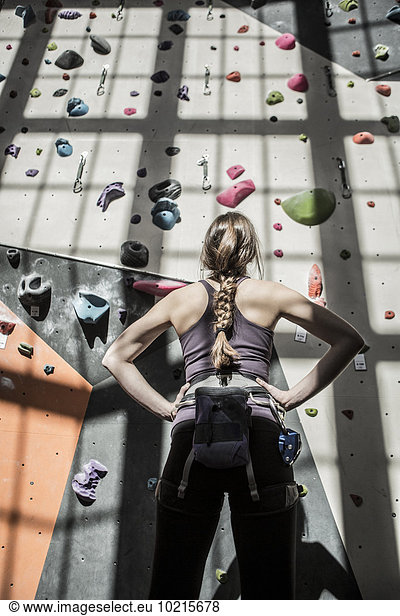 Athlete examining rock wall in gym