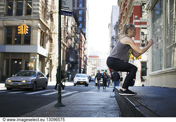 Athlete exercising at sidewalk in city