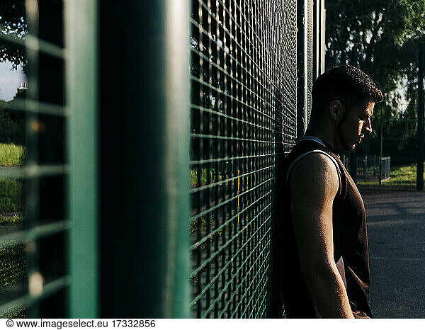 Athlete leaning on fence at basketball court