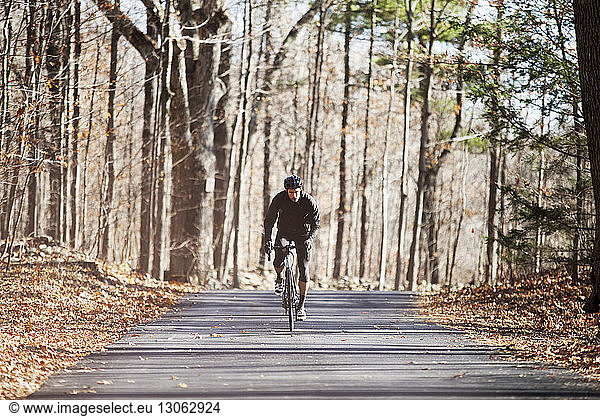 Athlete riding bicycle on road in forest