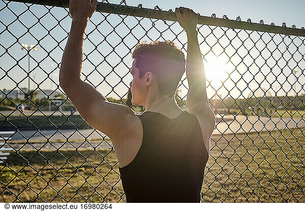 Athlete sports through fence on break during workout