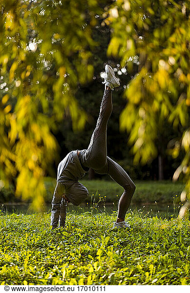 Athlete stretching while bending over backwards at park