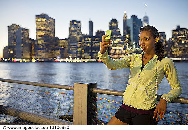 Athlete taking selfie while standing against river