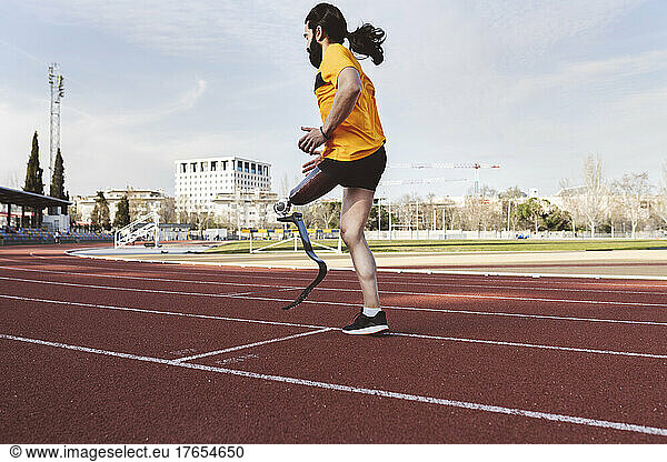 Athlete with prosthetic leg warming up on running track