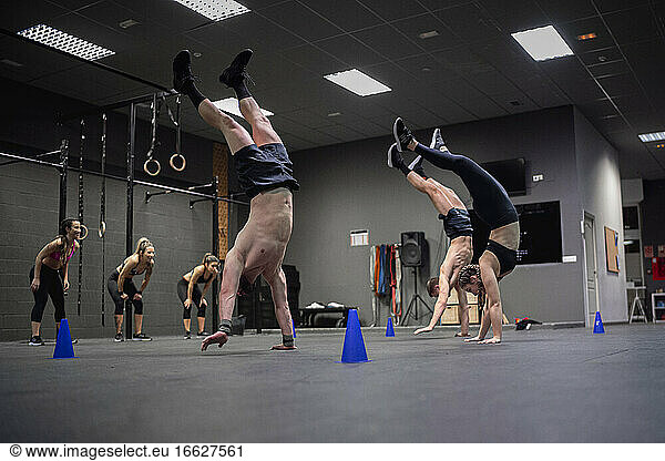 Athleten  die an der Hand laufen  mit motivierenden Frauen im Hintergrund im Fitnessstudio