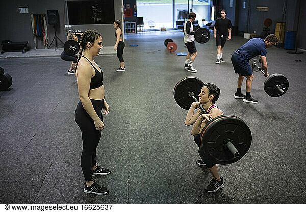 Athleten helfen sich gegenseitig beim Training im Fitnessstudio