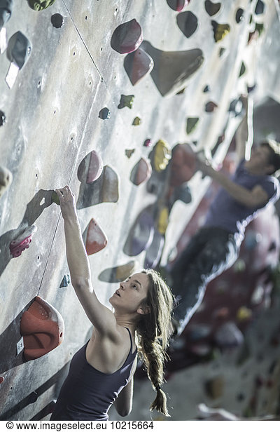 Athletes climbing rock wall in gym