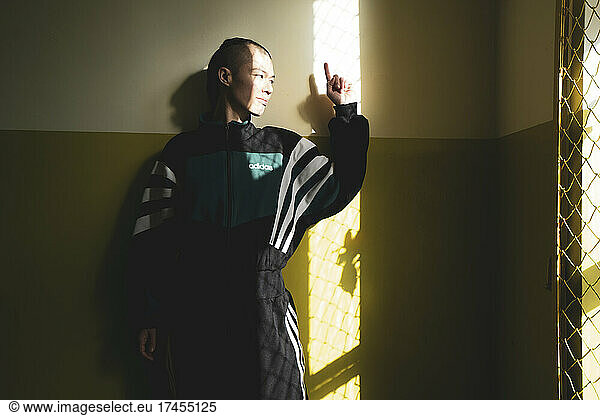 athletic androgynous strong woman stand in shadow and window sunlight