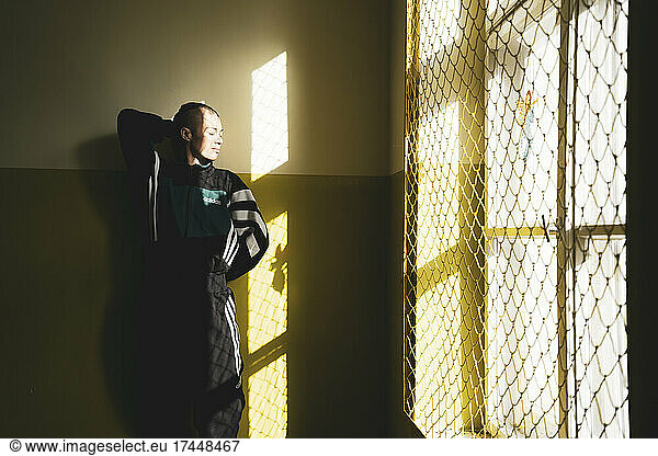 athletic androgynous strong woman stands in window sunlight in yellow