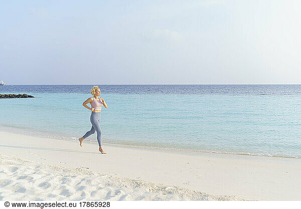 Athletic woman jogging on the beach.