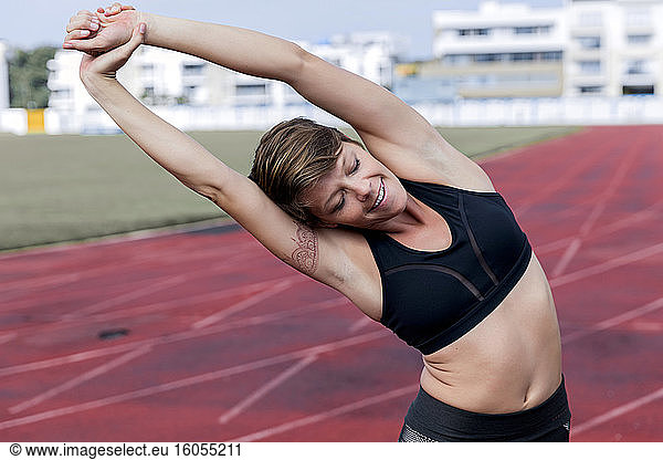 Athletic woman stretching on tartan track