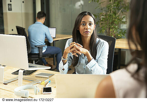 Attentive businesswoman listening to colleague in office