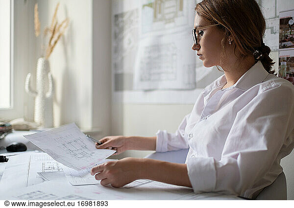 Attentive businesswoman reading draft in office