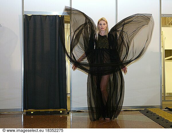 Attractive fashion model in flying long silk dress at backstahe of fashion show