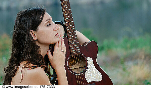 Attractive long haired  looking at her guitar. Young  beautiful model